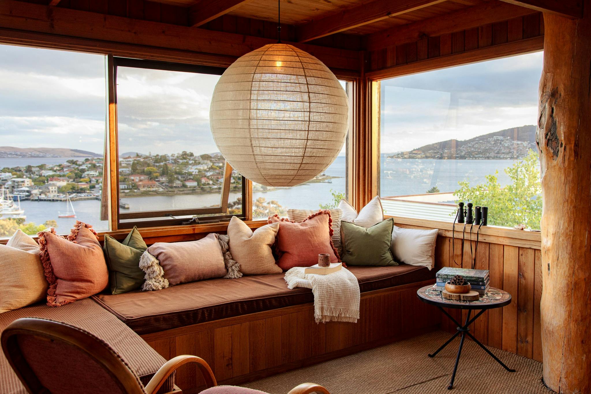 A large daybed, window seat, featuring a linen lantern lightshade.
