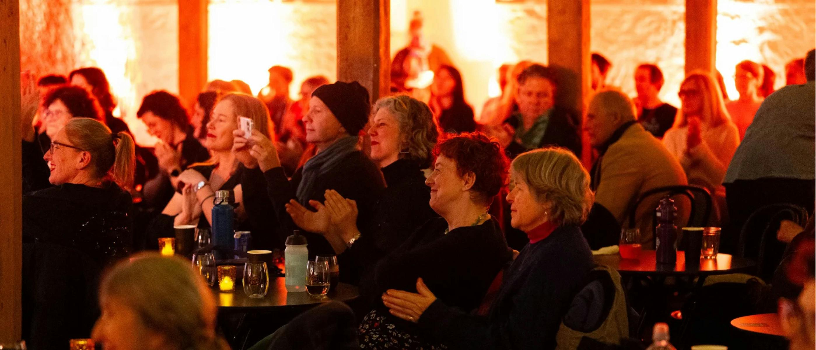 A group of people smiling and clapping sitting in an indoor venue