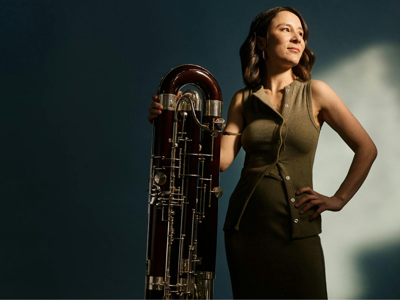 A photograph of a contra bassoon with its player standing beside