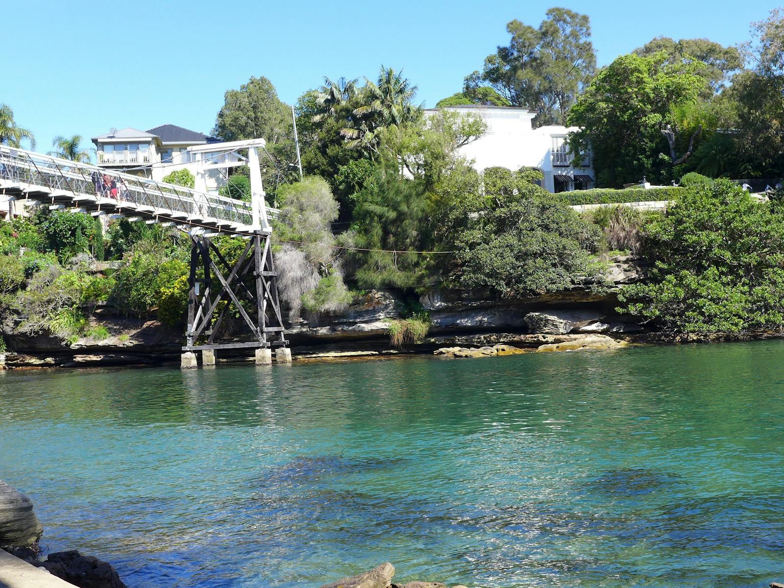 a tranquil inlet of Sydney Harbour with a beach and a shark netted swimming pool