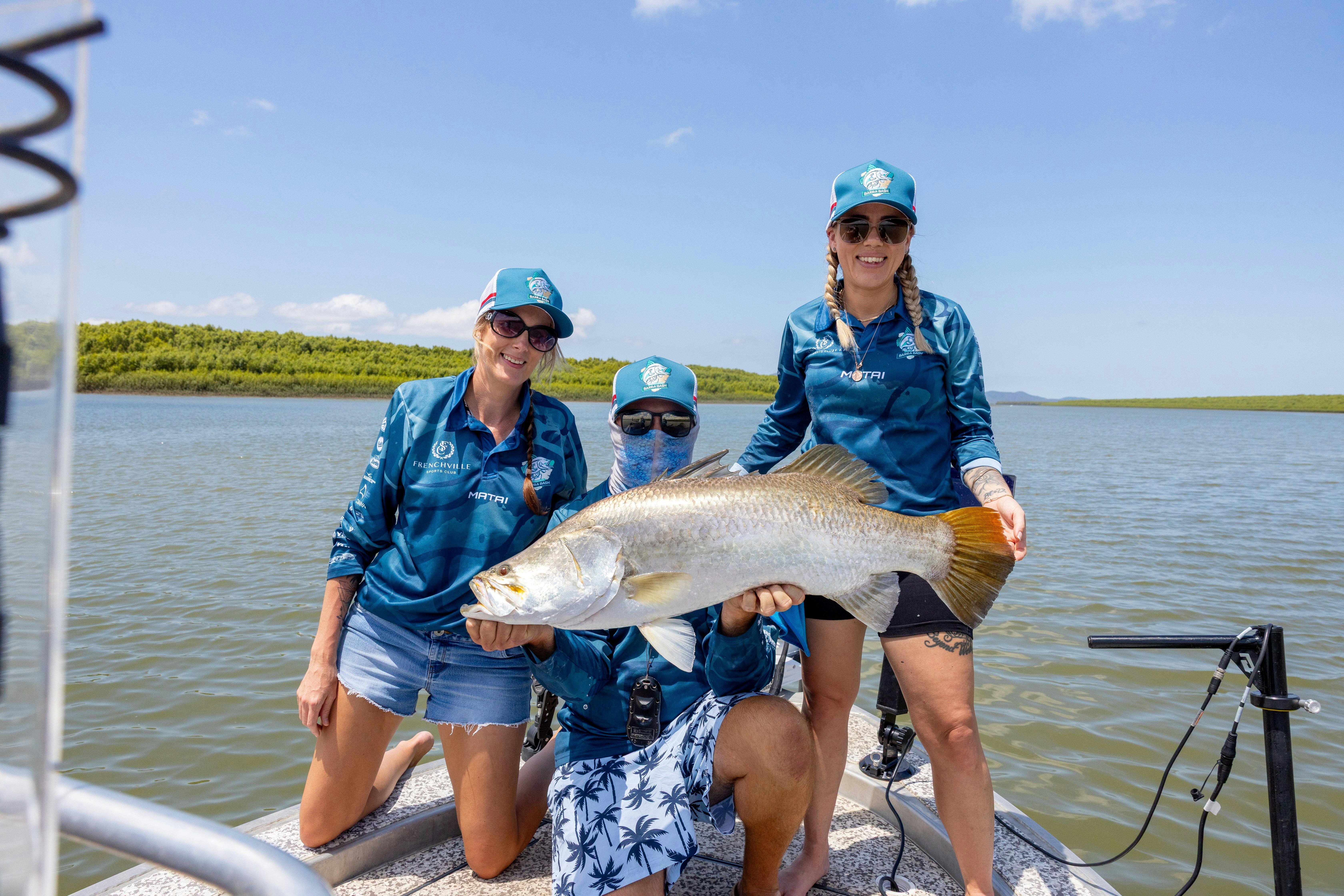 Two anglers holding a barramundi on a boat on the Fitzroy River.