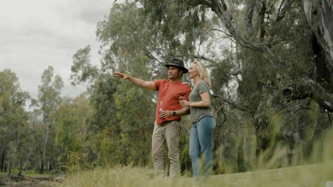 A man and woman look across the bank of the Murray River in Howlong.