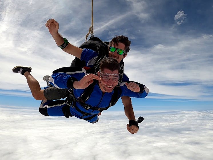 Tandem Skydive between two layers of cloud.  Young male instructor and passenger.  Big smiles!