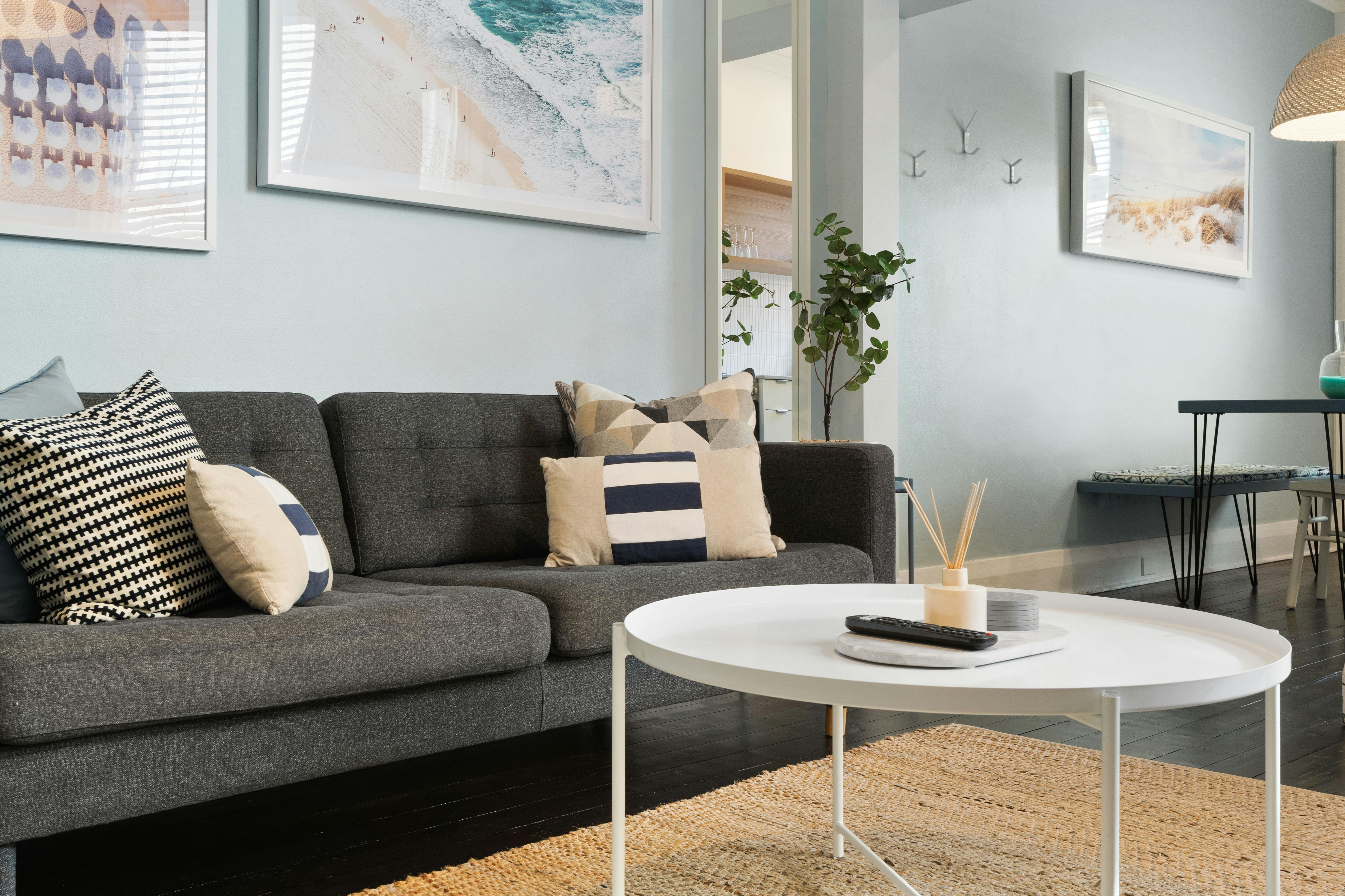 Bright living area with cozy furniture, plants, and beach-themed art.