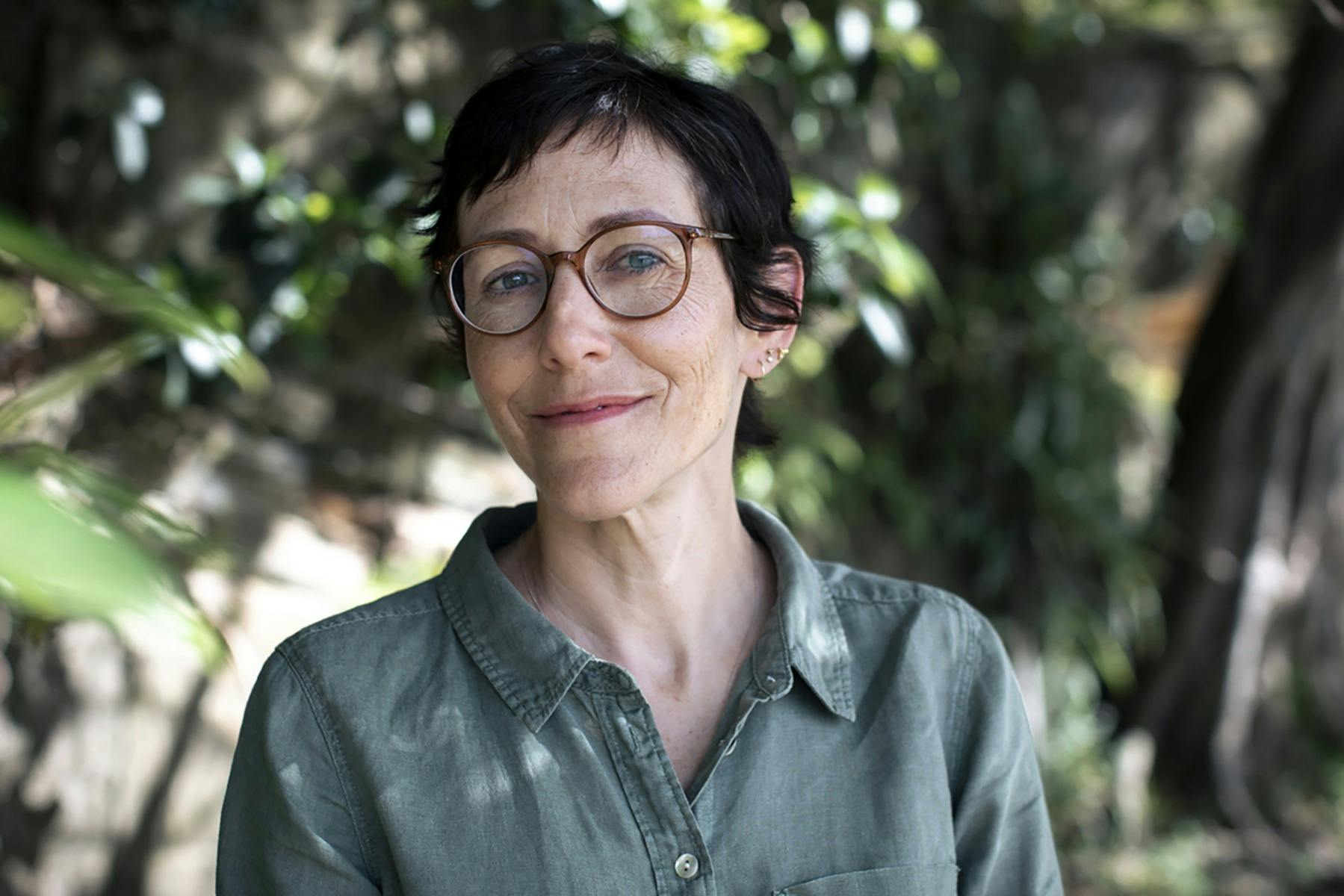 A woman wearing glasses smiling outdoors