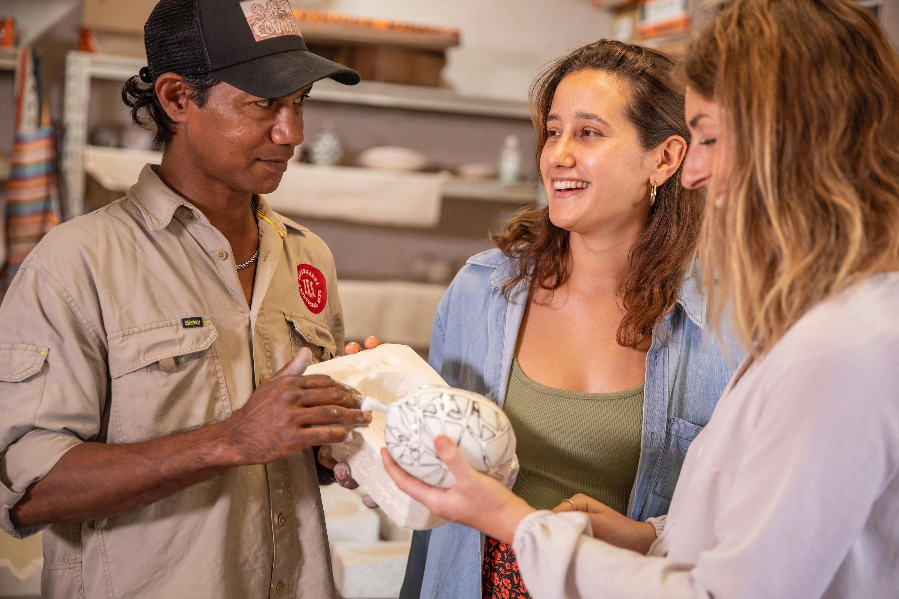 Waringarri artist shows ceramic work to visitors.