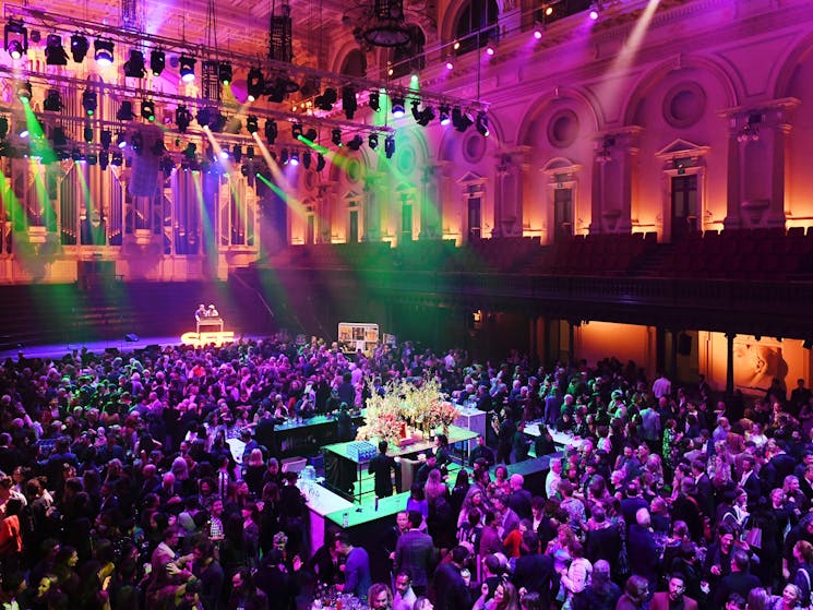 A large room of people partying with green and purple lights