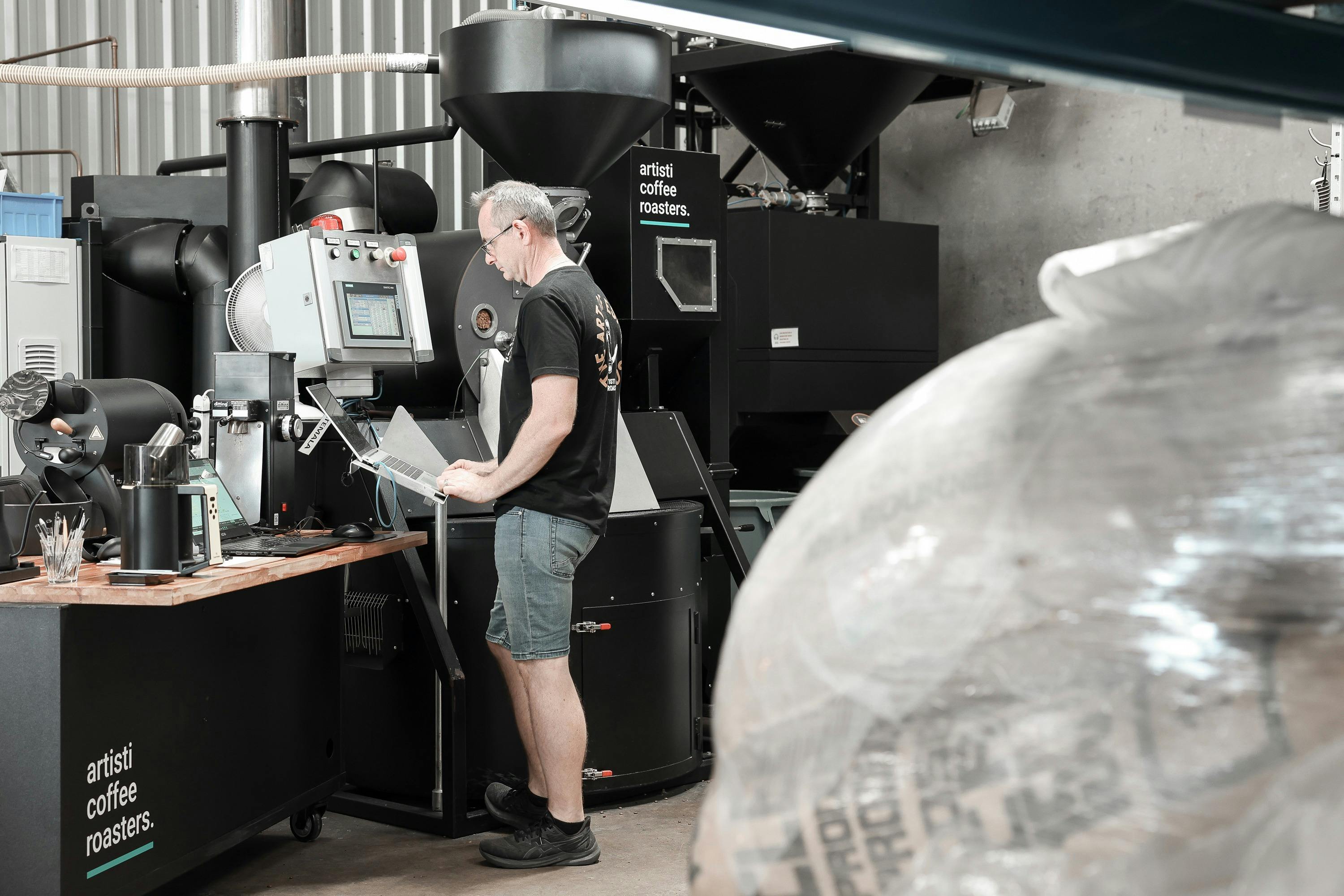 A man roasting coffee beans on an IMF hot air coffee roaster.