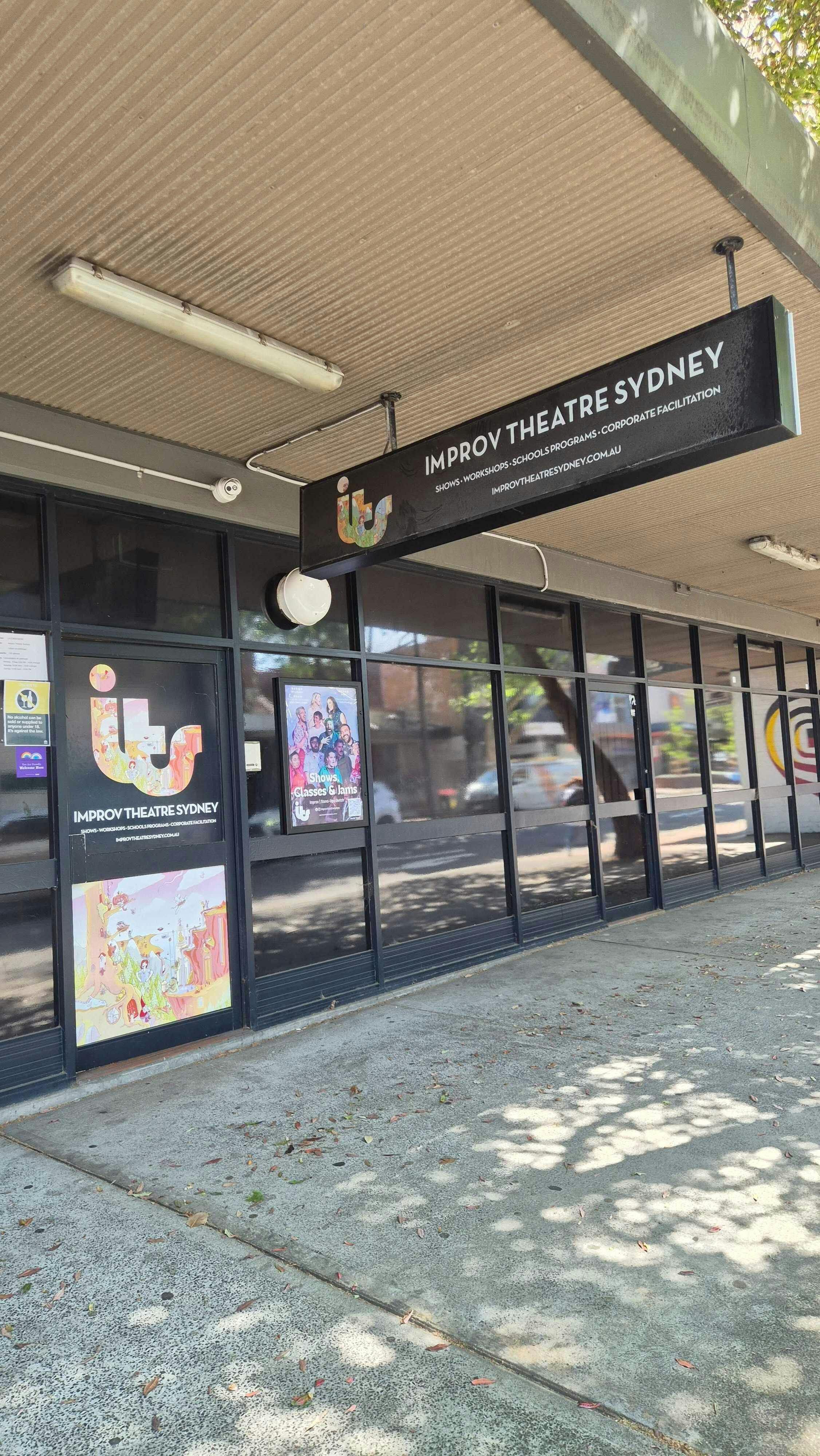 Outside the venue. Door and awning sign that say Improv Theatre Sydney.