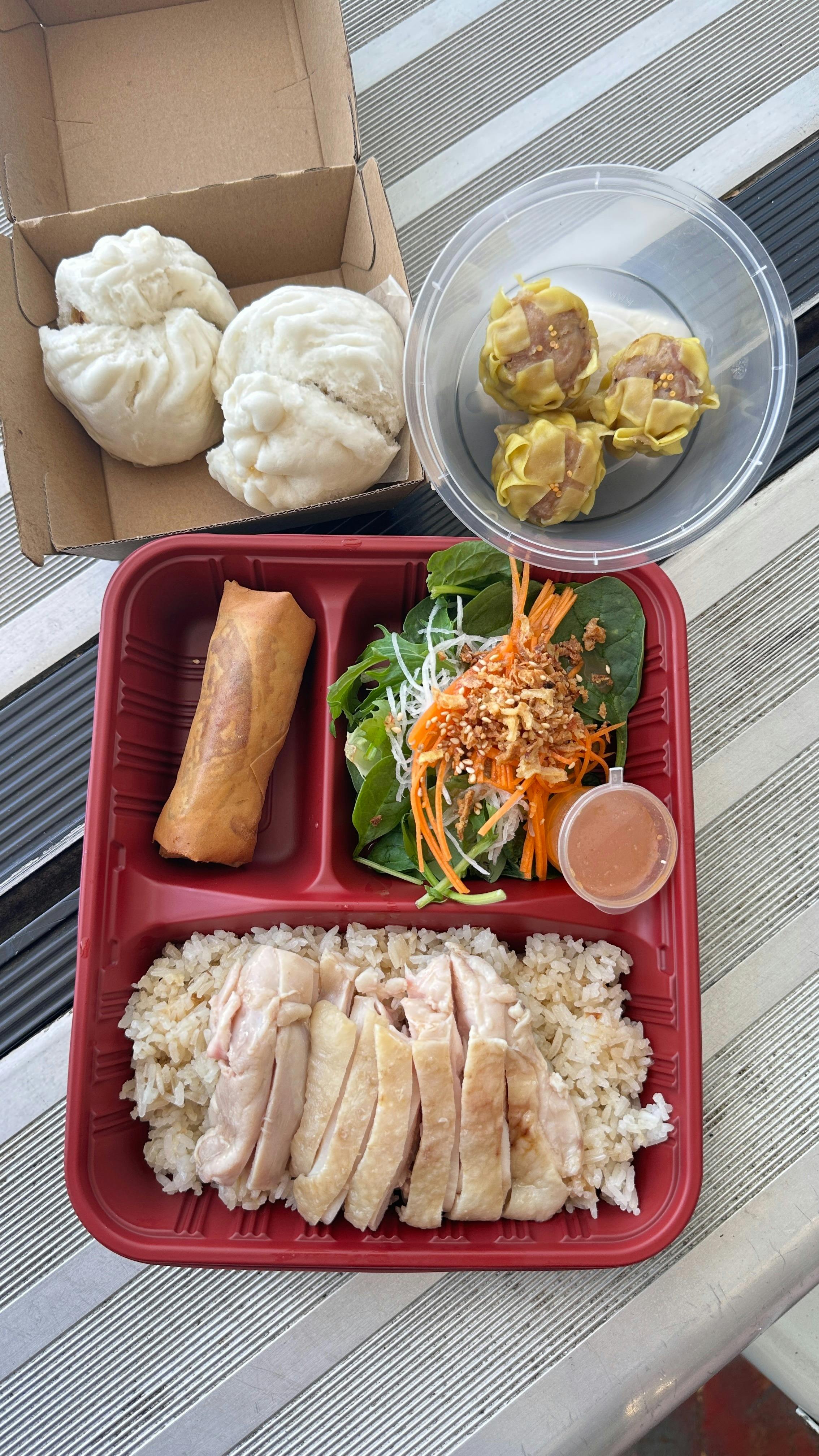 chicken rice with sliced poached chicken, fragrant rice, greens, spring roll, and side salad.