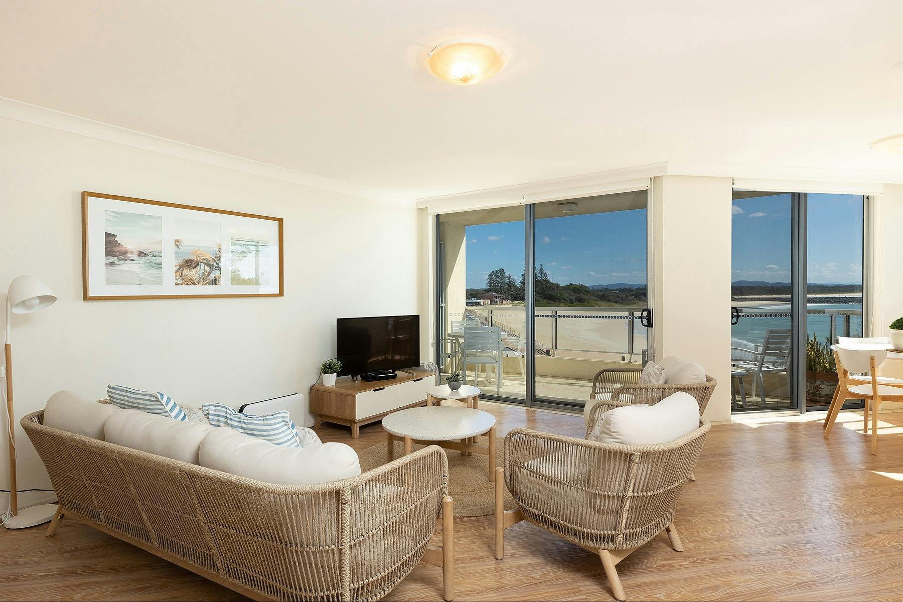 Lounge room with modern rattan lounge, TV and ocean views