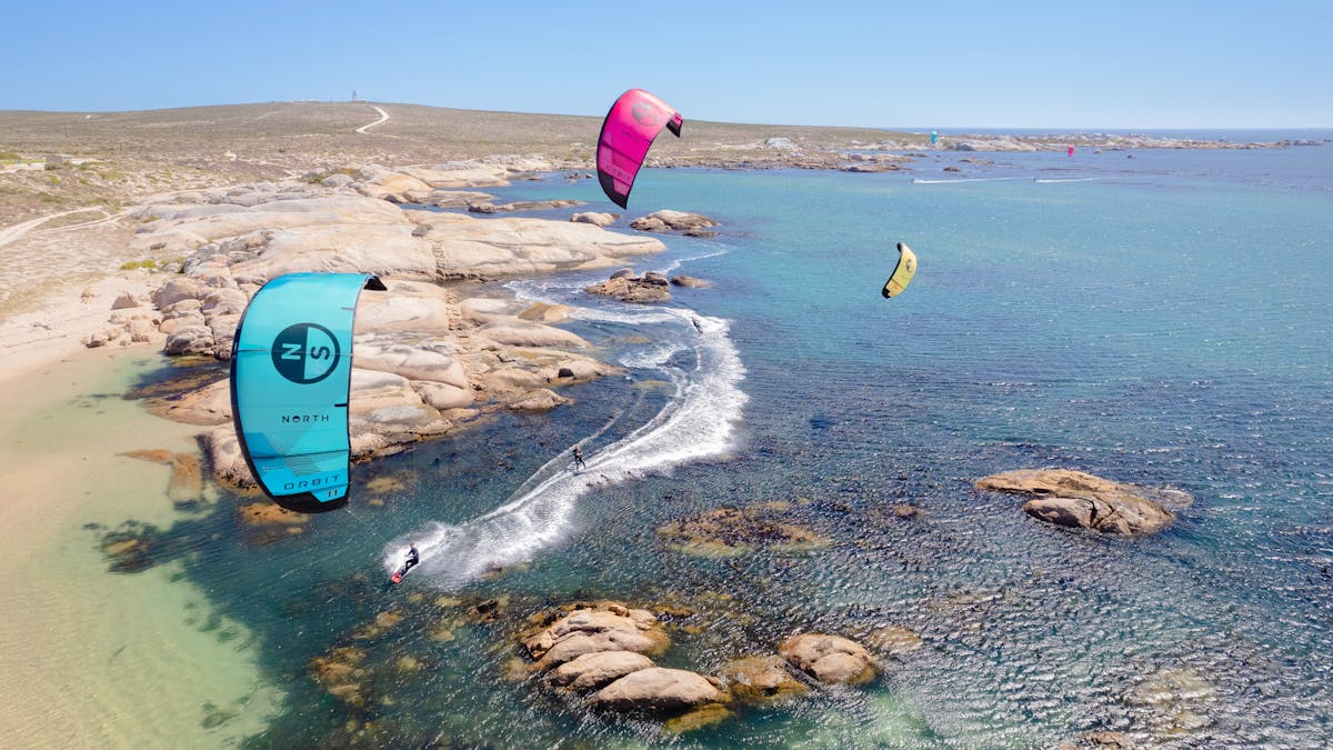 Aerial Photo of three kitesurfers in a beautiful clear water location