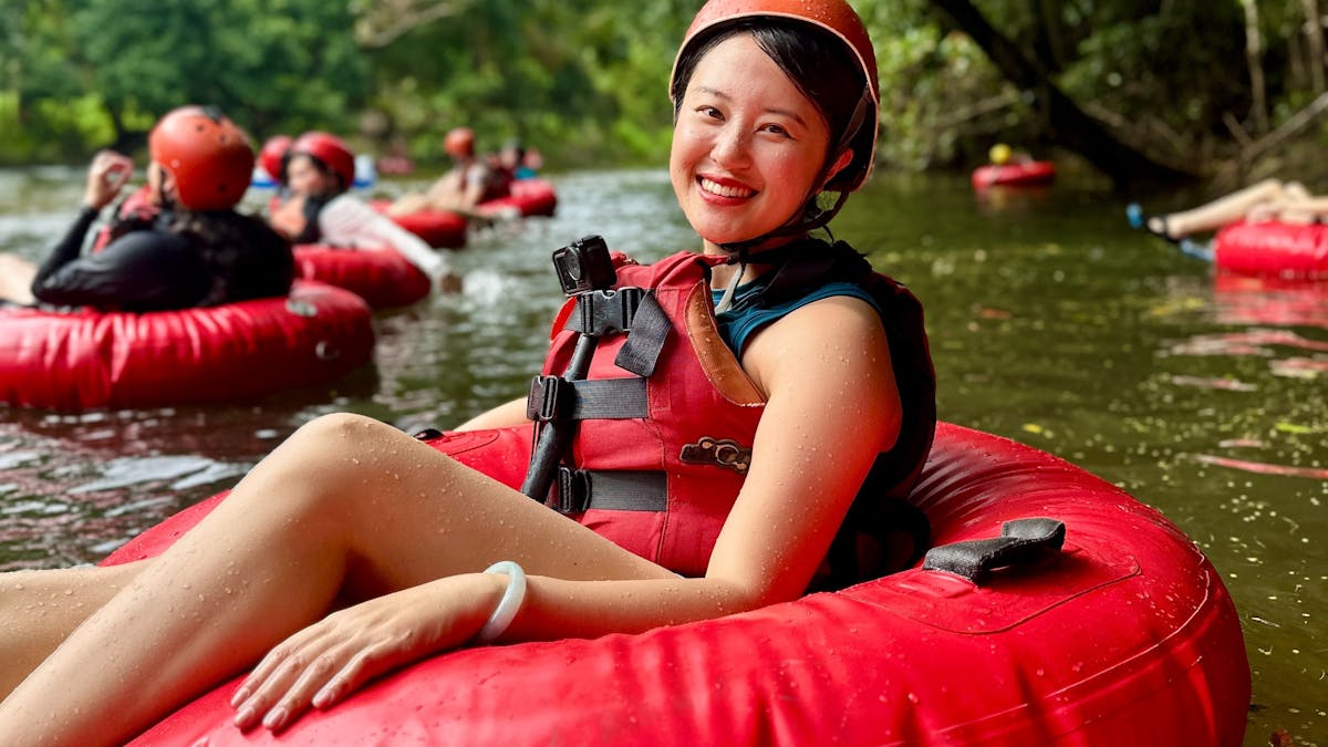 Woman in red tube and safety gear posed smiling at the camera as she floats down the Litlle Mulgrave Woman in red tube and safety gear posed smiling at the camera as she floats down the Litlle Mulgrave