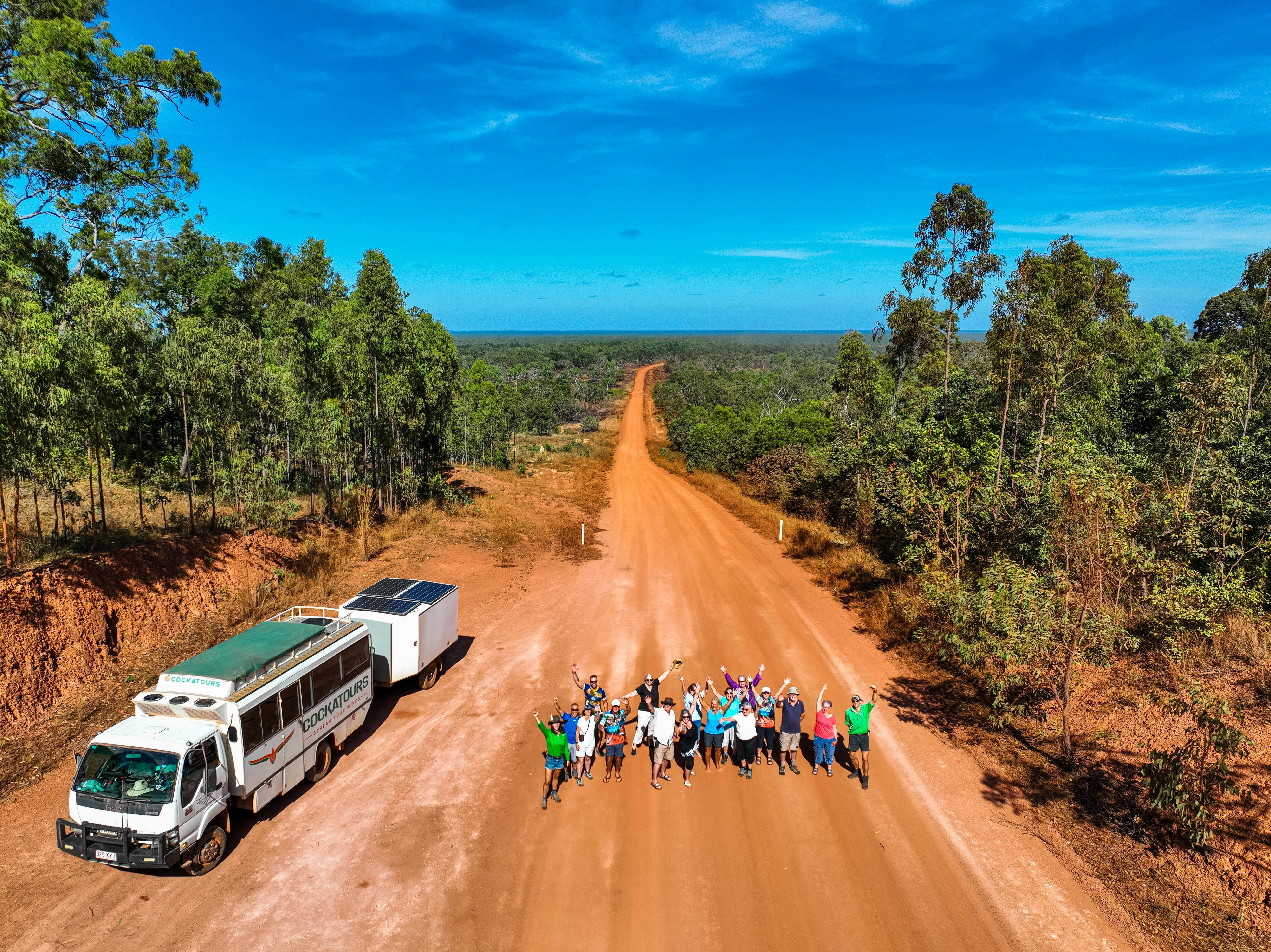 group jumping on dirt road next to truck