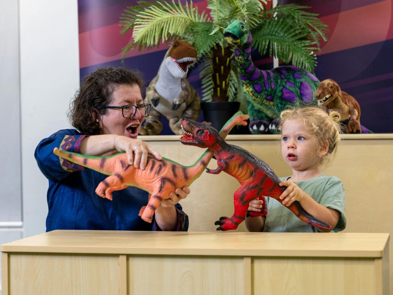 A young child and their grandma play with dinosaurs at Science Time