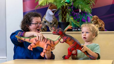 A young child and their grandma play with dinosaurs at Science Time