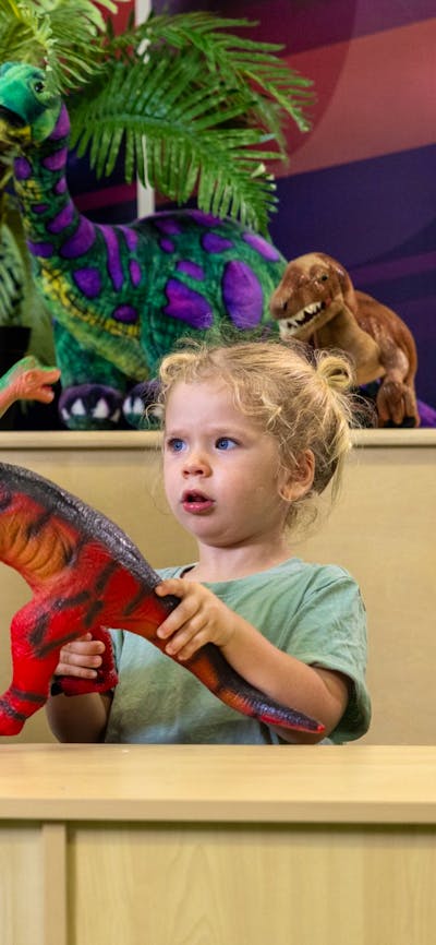 A young child and their grandma play with dinosaurs at Science Time