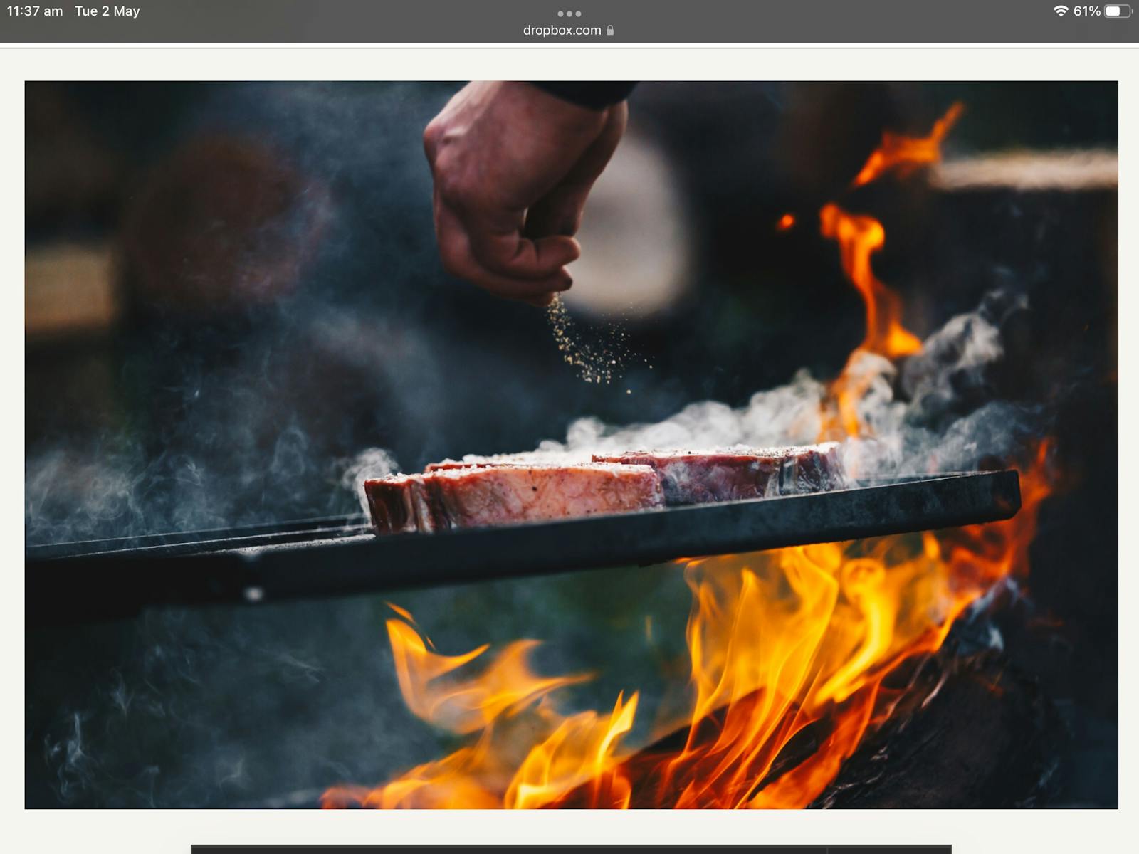 Two Cape Grim Scoth Fillets sizzling over an open flame. Had sprinkling seasoning onto steak.