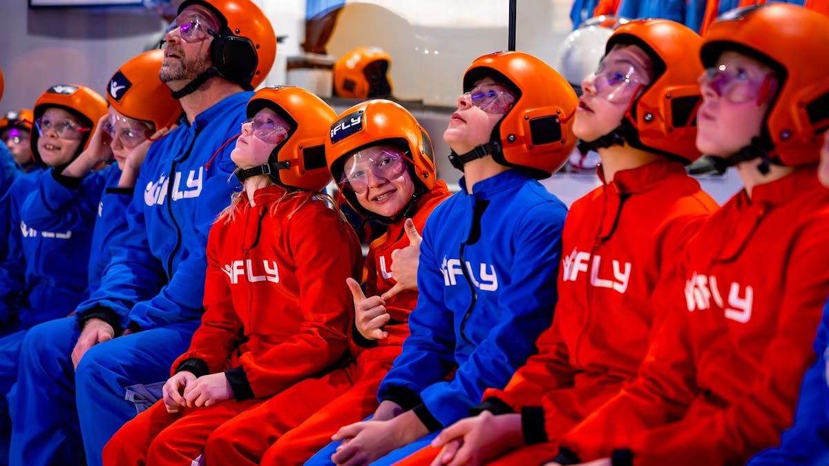 Kids and families in suits watching others fly while awaiting their turn.