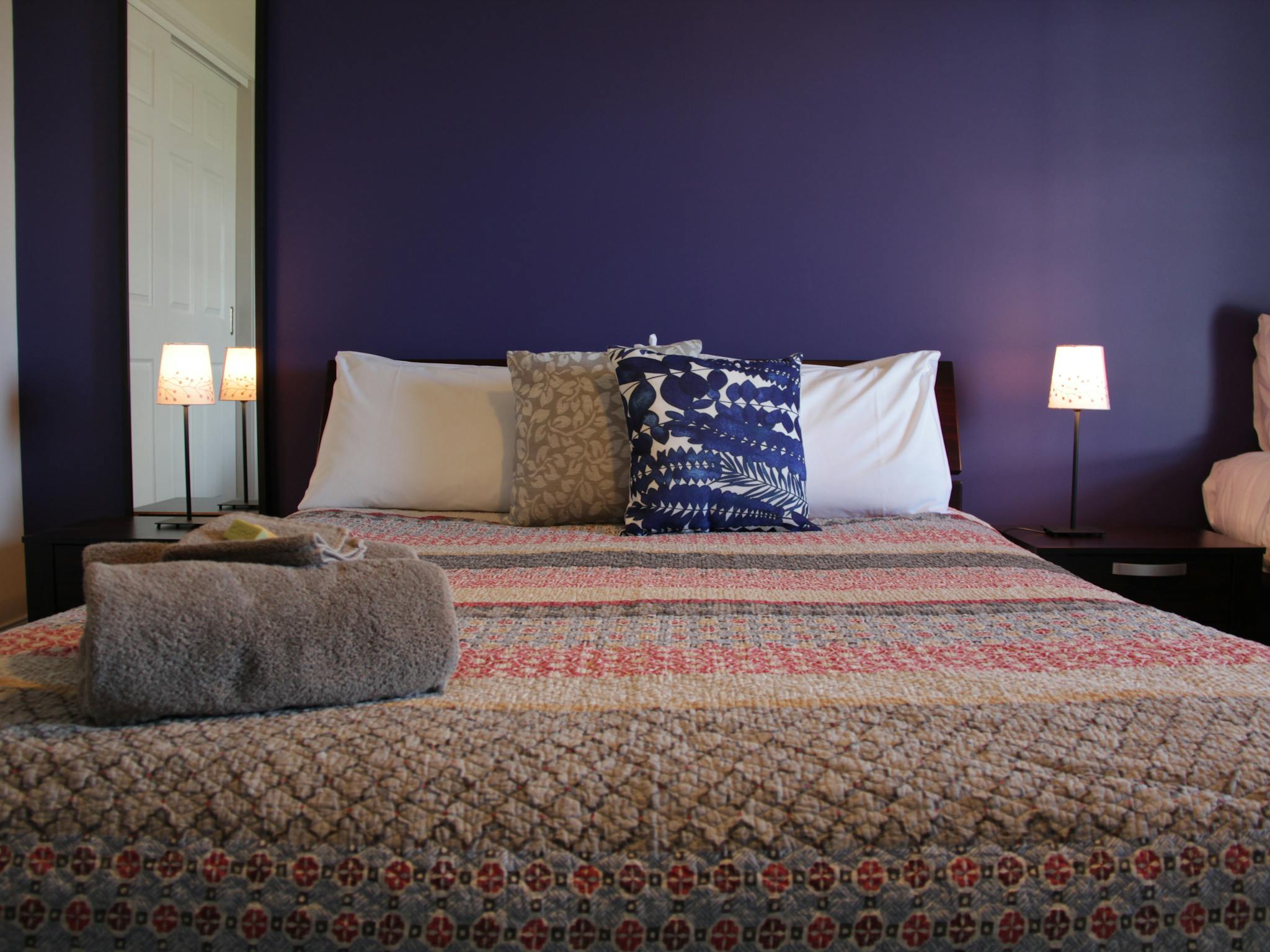 Queen size bed and a single bed in a room with a purple wall