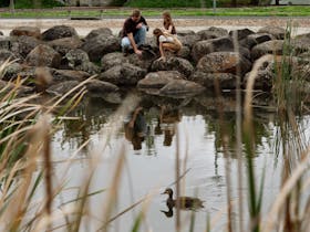 Family sitting on rocks next to pond