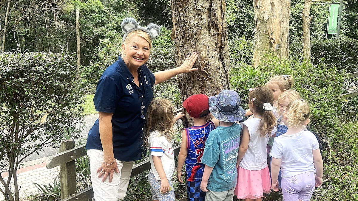 Ranger STacey and a group of children feeling the texture of the tree