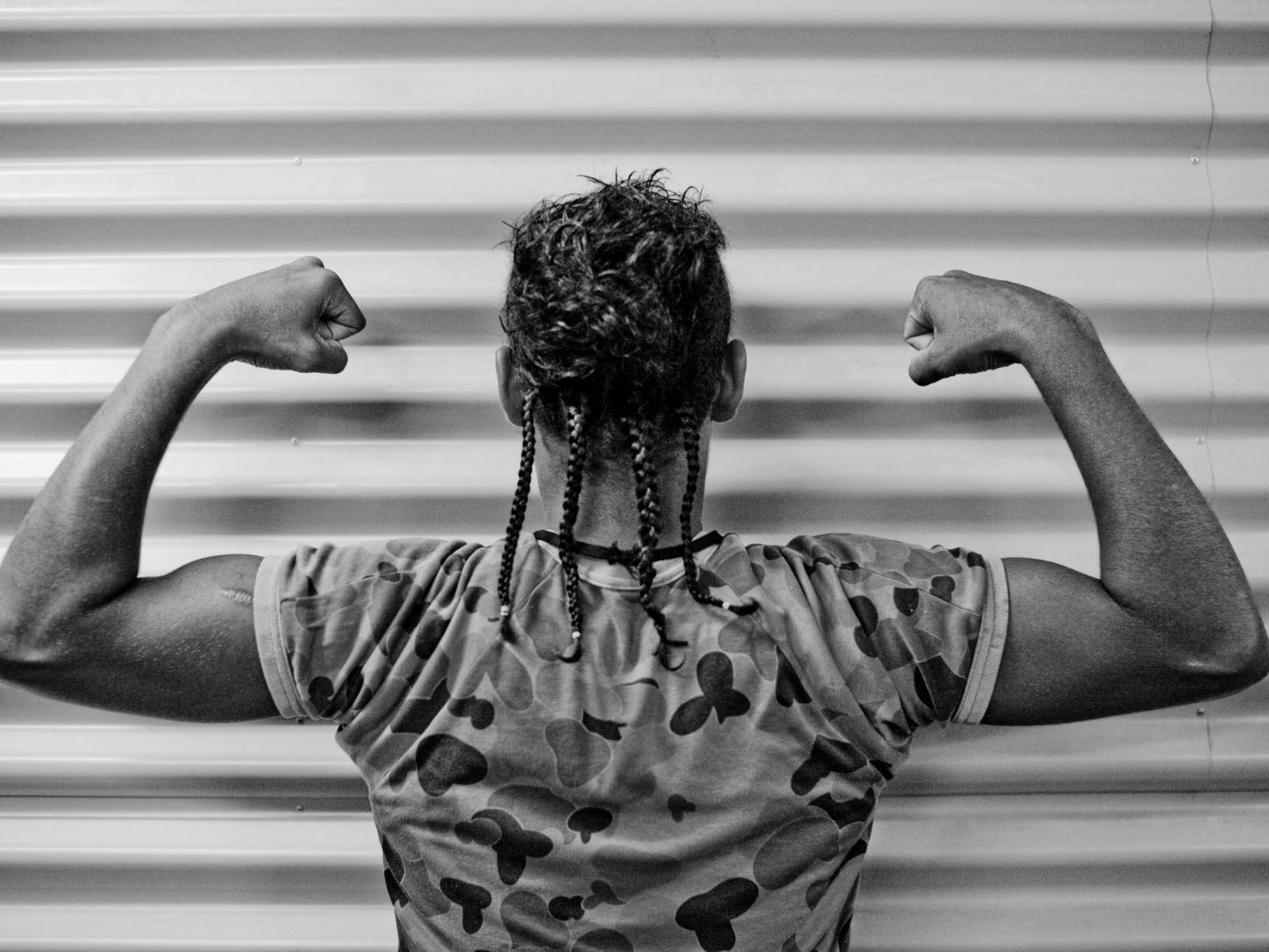 black and white photo of man's back flexing his arms