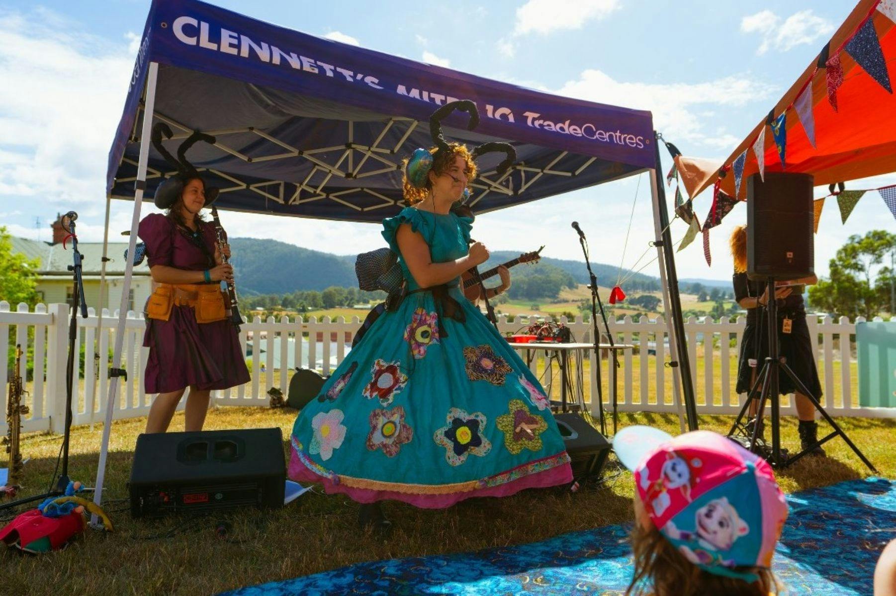 Girl on stage in f costume, decorated with flowers and insects.  Standing on a stage and