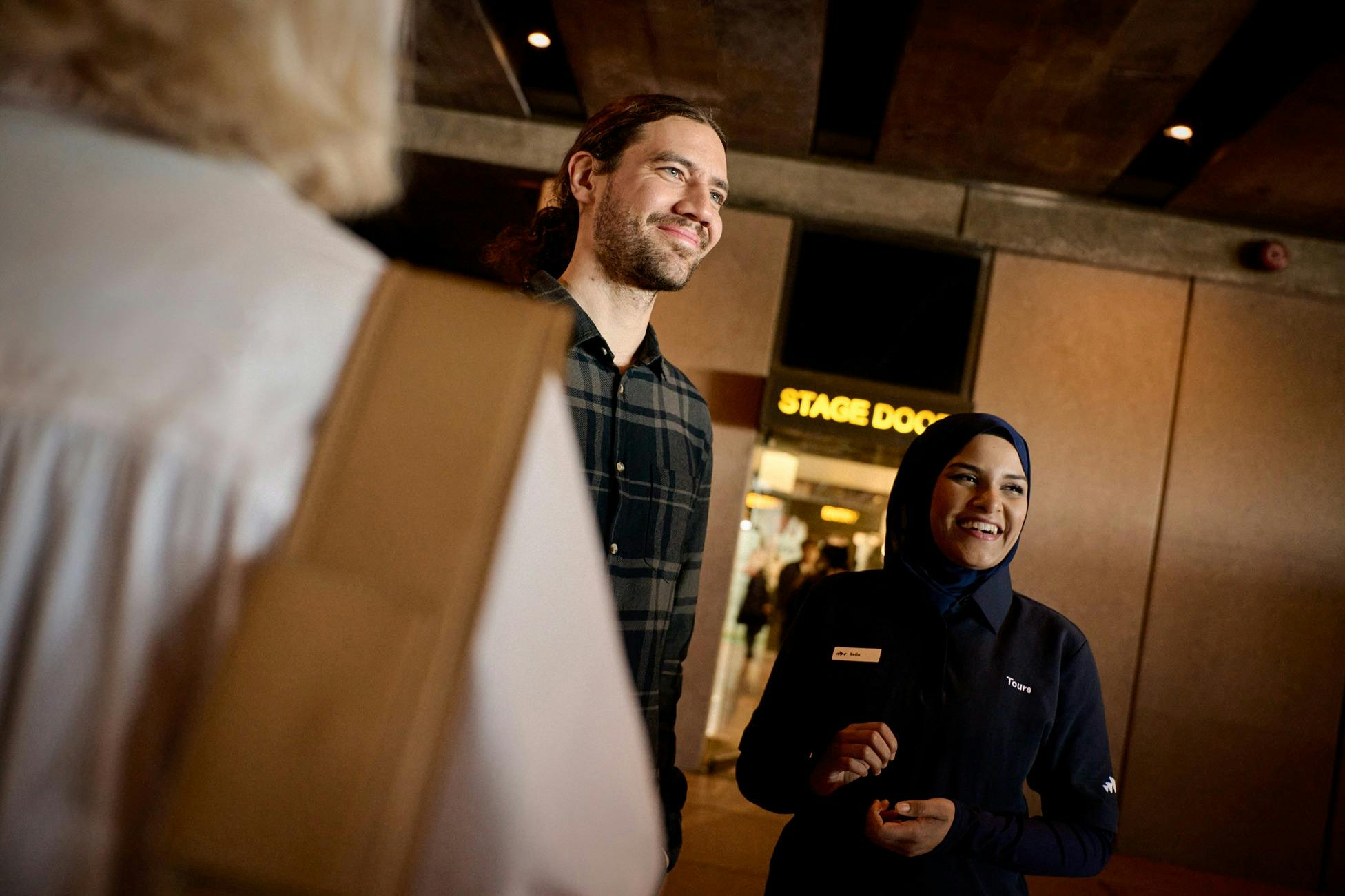 Tour guide and a man both smiling outside of Stage Door