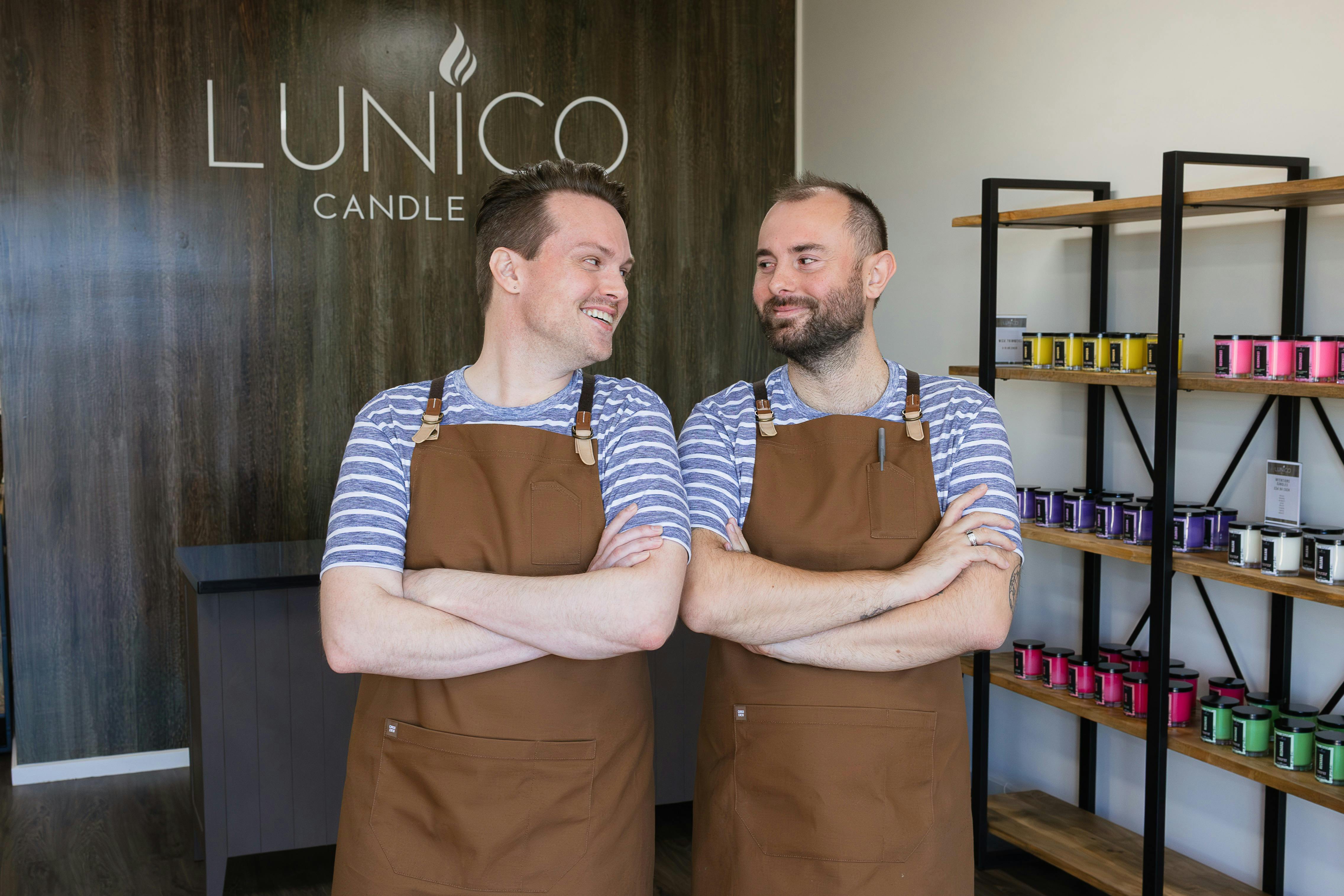 Business owners Will and Jake in the shop with the Lunico Candle Co. logo in the background.