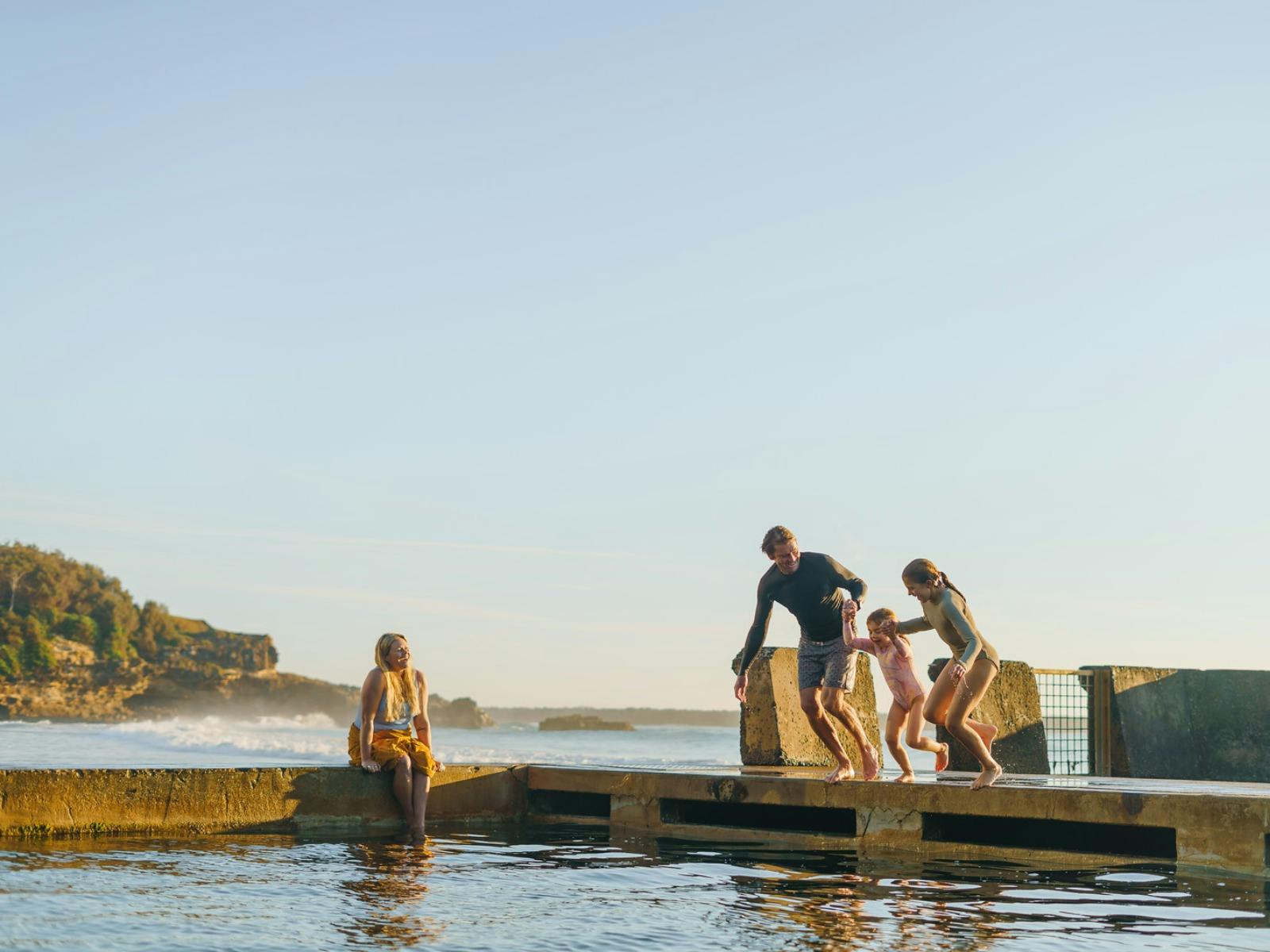 Family jumping into Yamba Ocean Pool