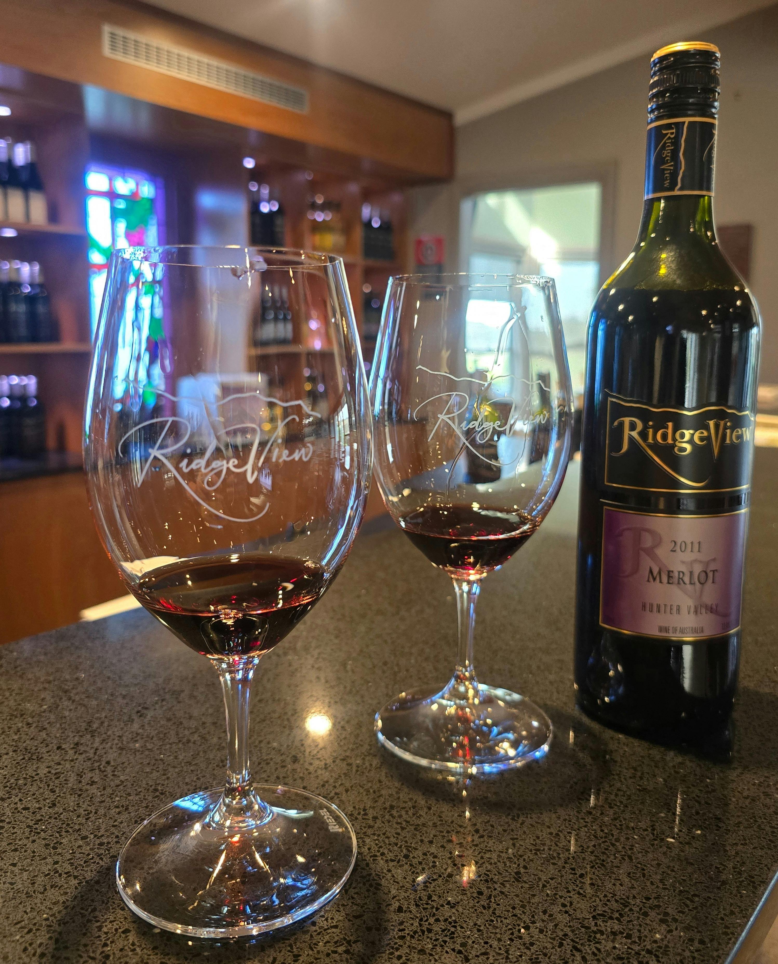 Bottle of wine and two tasting glasses on a winery tasting counter.