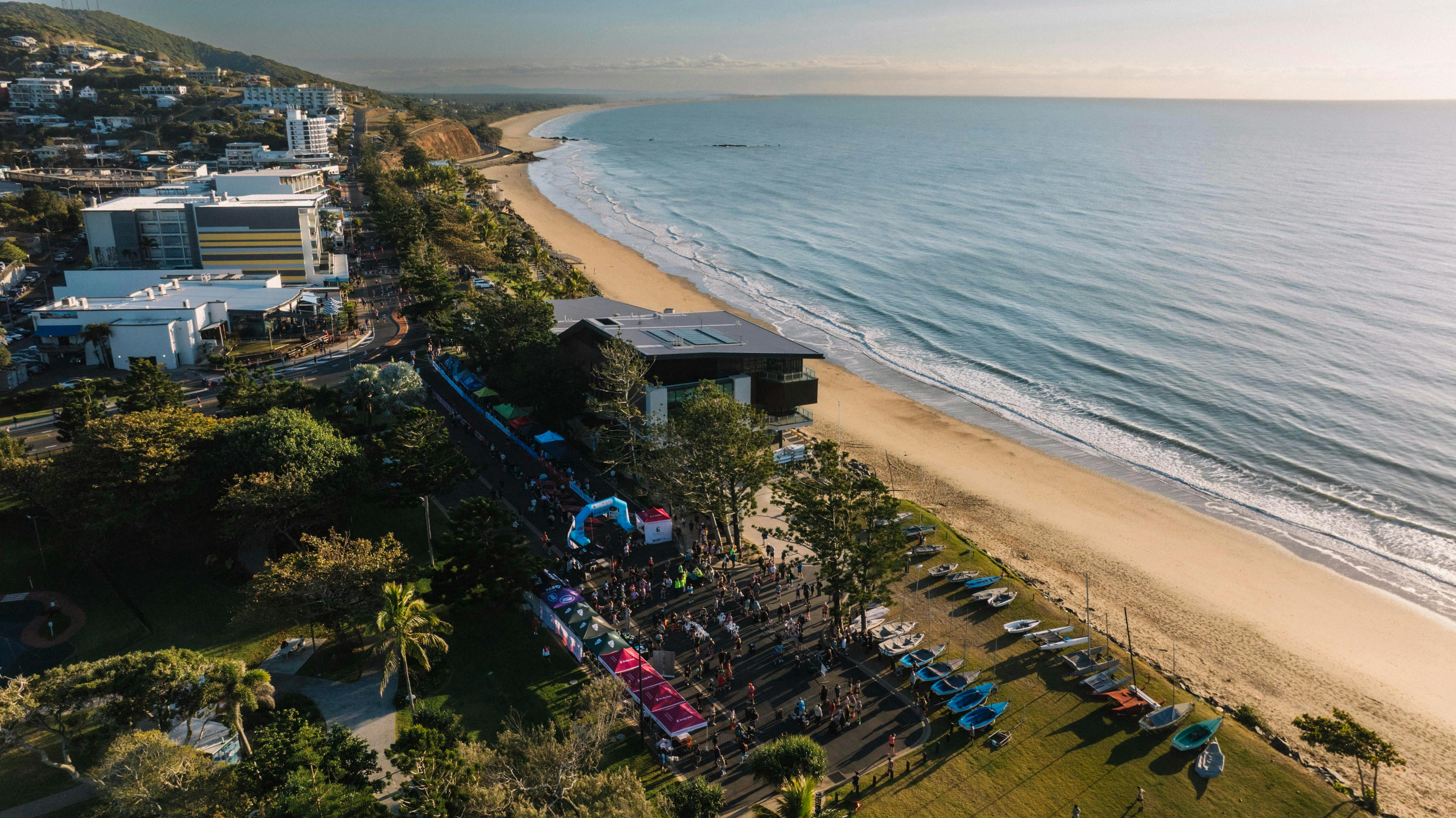 Aerial view of Yeppoon’s beachfront, coastal town and long sandy beach beside the ocean.