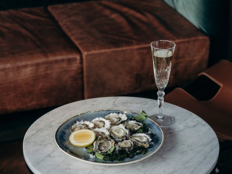 Oysters sitting on a small table with a crystal glass of champagne sitting next to it