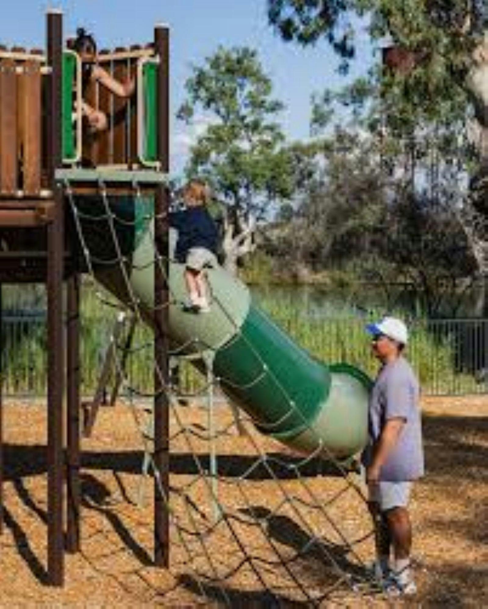 Image of father watching children playing at parkk
