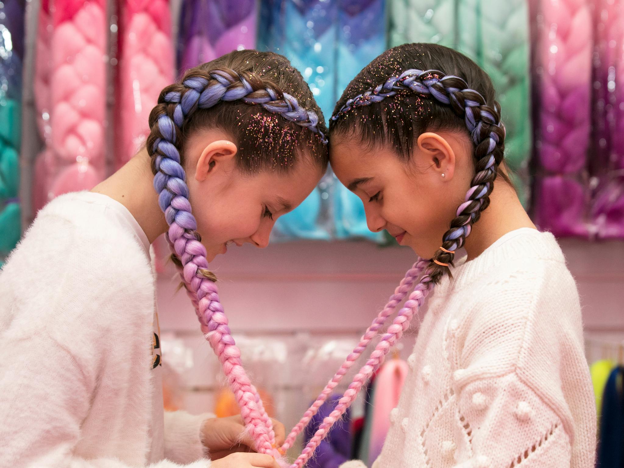 two girls with their heads together and their hair braids are forming a love heart shape two girls with their heads together and their hair braids are forming a love heart shape
