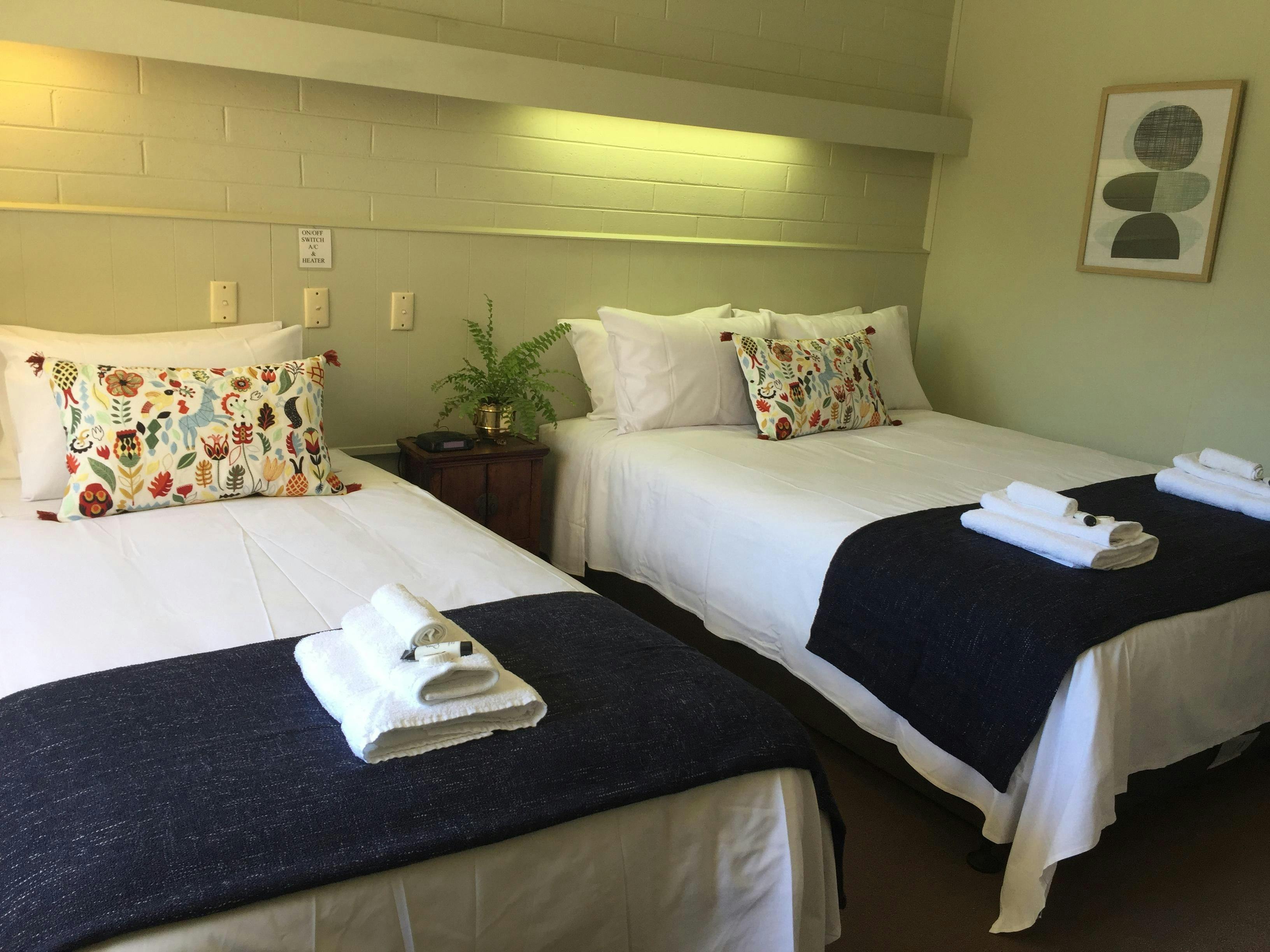 Modern, well-appointed motel room featuring two comfortable single beds with crisp white linens
