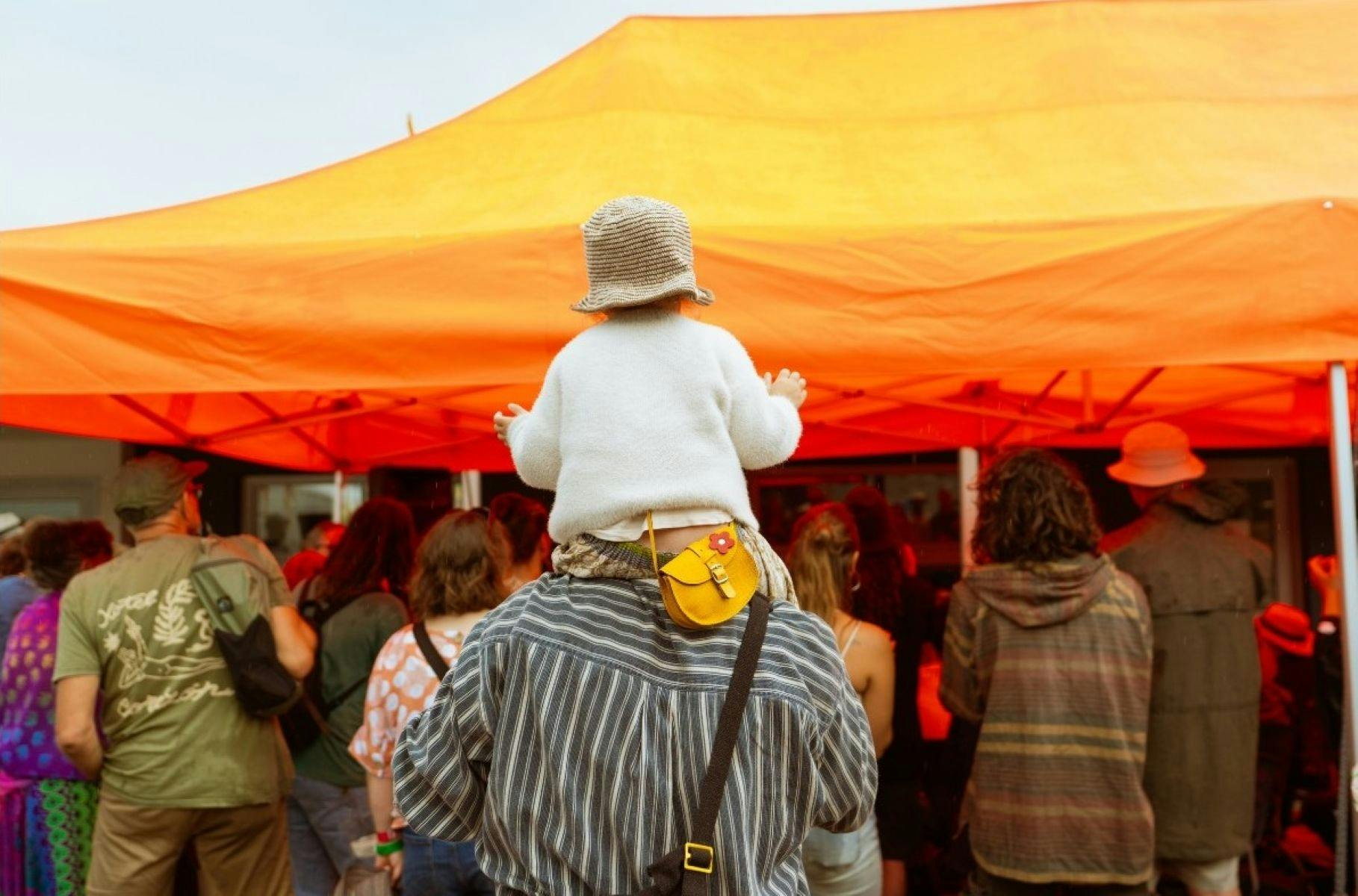 Child sitting on adults' shoulders in the festival crowd