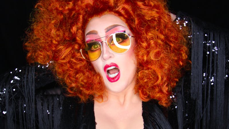 Bold Red Haired woman with sunglasses on and her mouth open with red lipstick