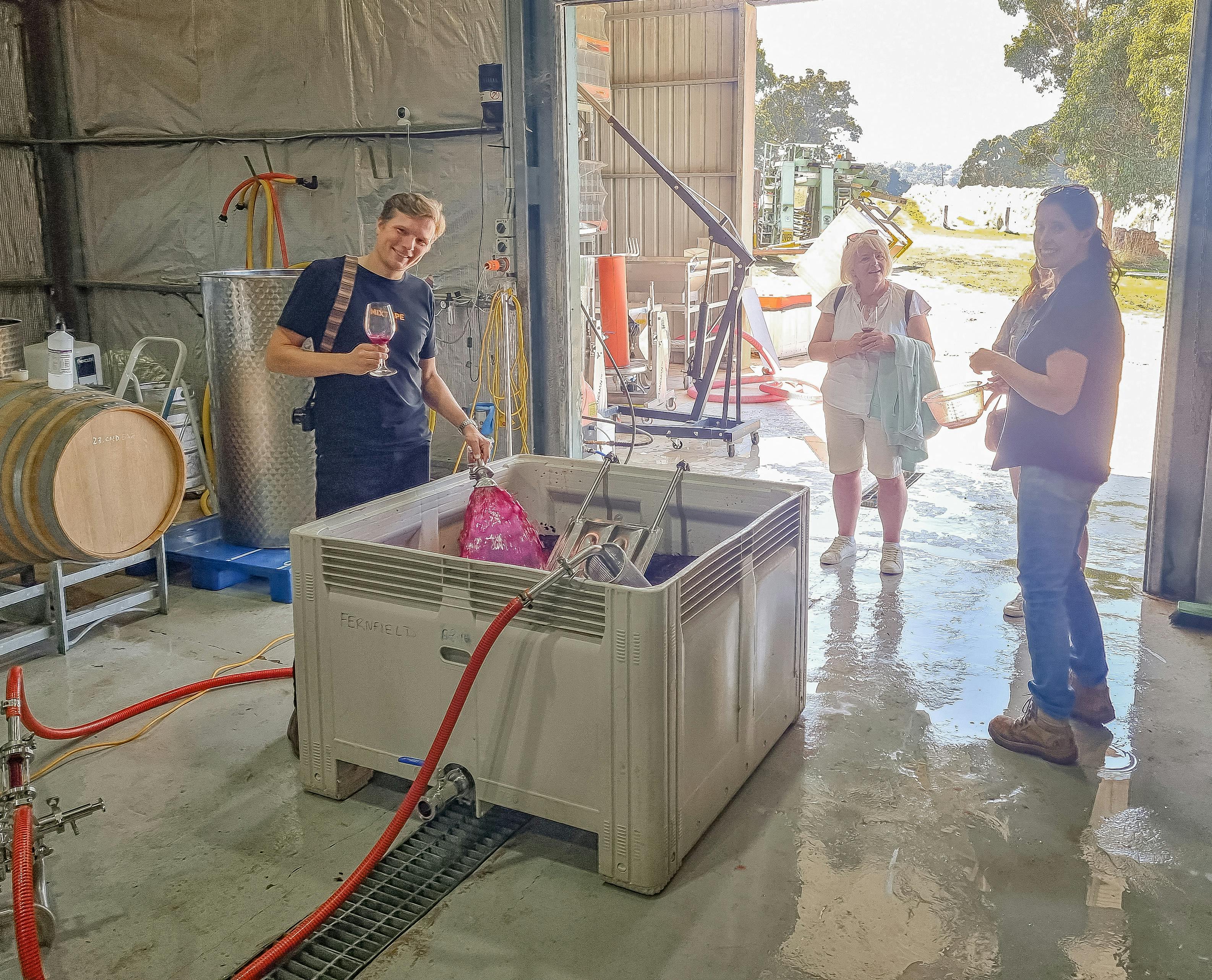 A man holding a hose pumping over a wine ferment