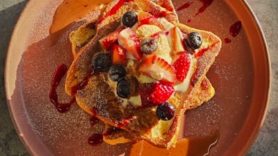 French Toast served with Berries and Sauce on a Brown plate