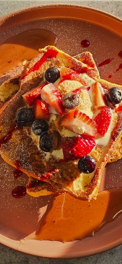 French Toast served with Berries and Sauce on a Brown plate