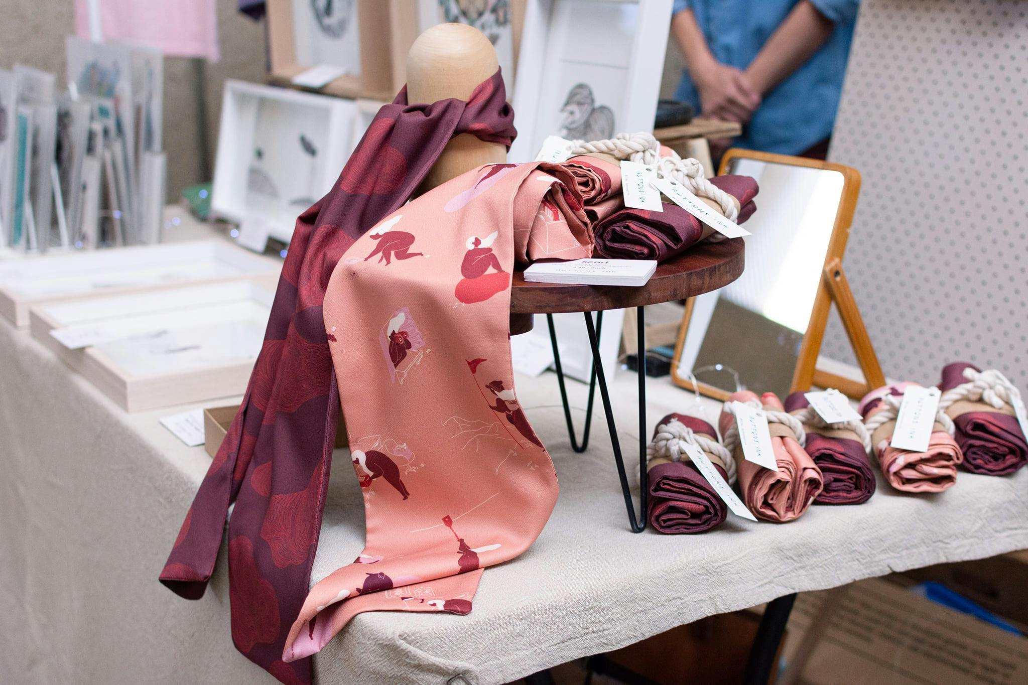 A close up of silk scarfs in pink and maroon with original artist patters on them