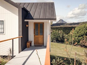 Walkway to entrance door of your cabin with a view of the cow paddock and Glasshouse Mountain behind
