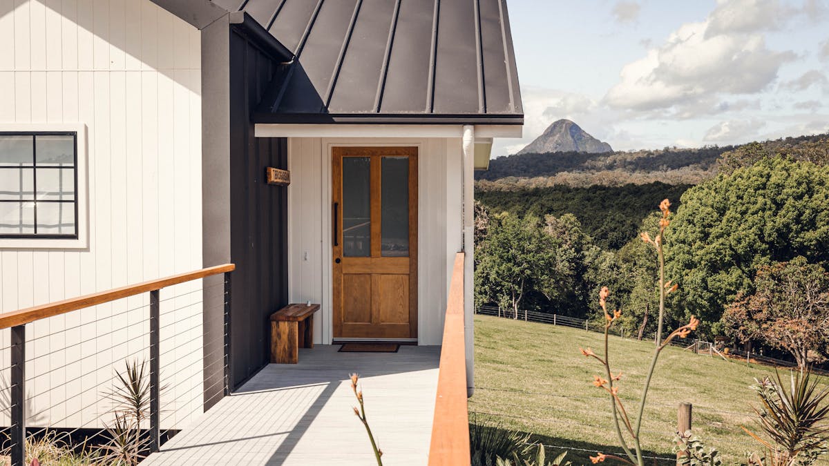 Walkway to entrance door of your cabin with a view of the cow paddock and Glasshouse Mountain behind