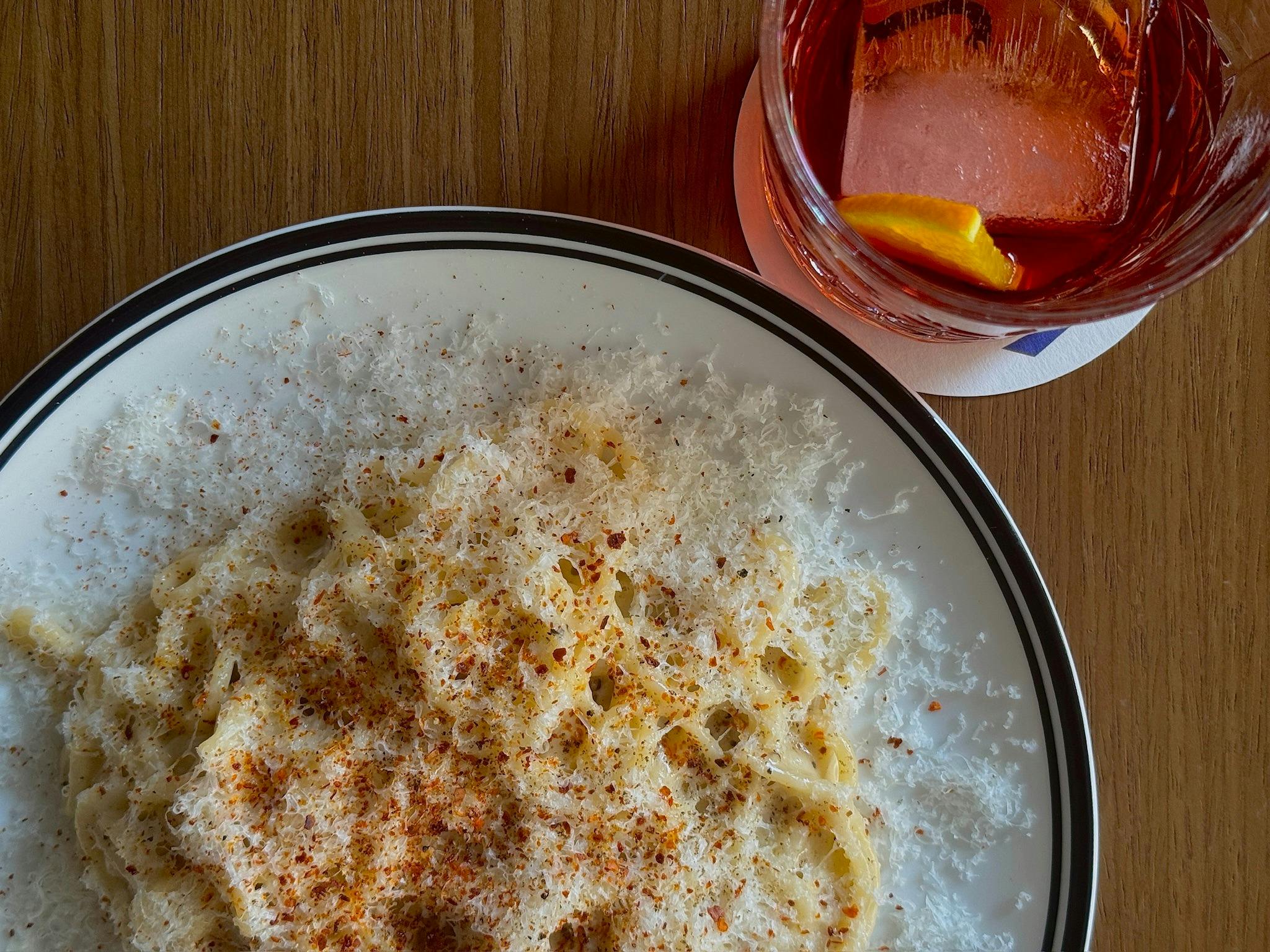 A plate of cacio e pepe dusted with cheese and Aleppo pepper
