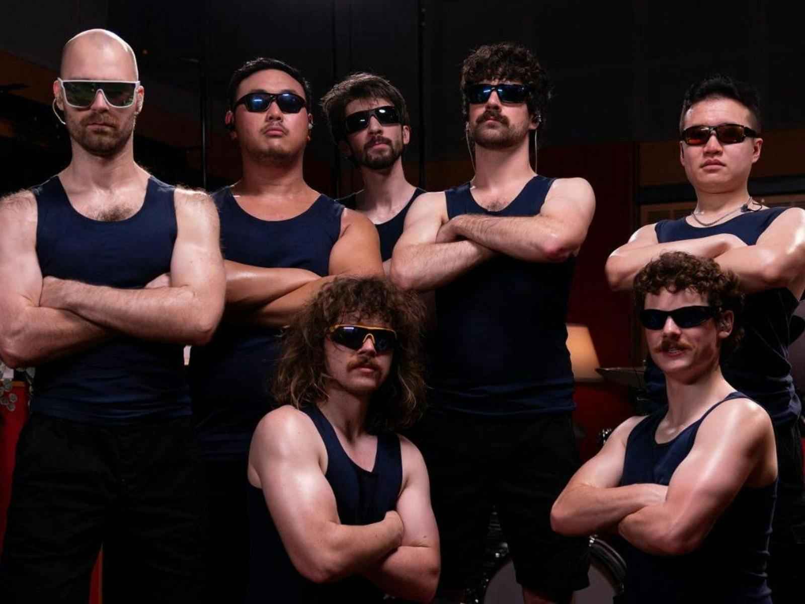 7 band members wearing tank tops with their arms all crossed