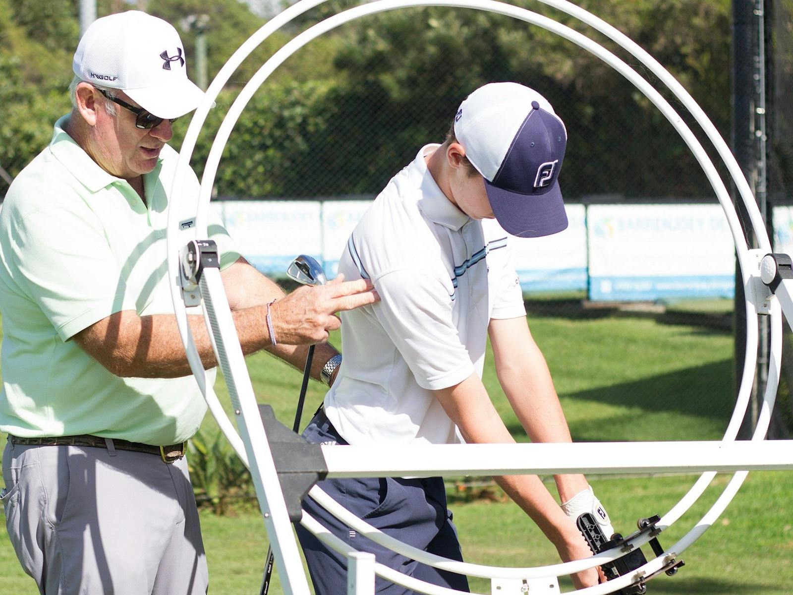 Pittwater Golf Centre - PGA Professional Trainer Dave Saunders teaching student with training aid