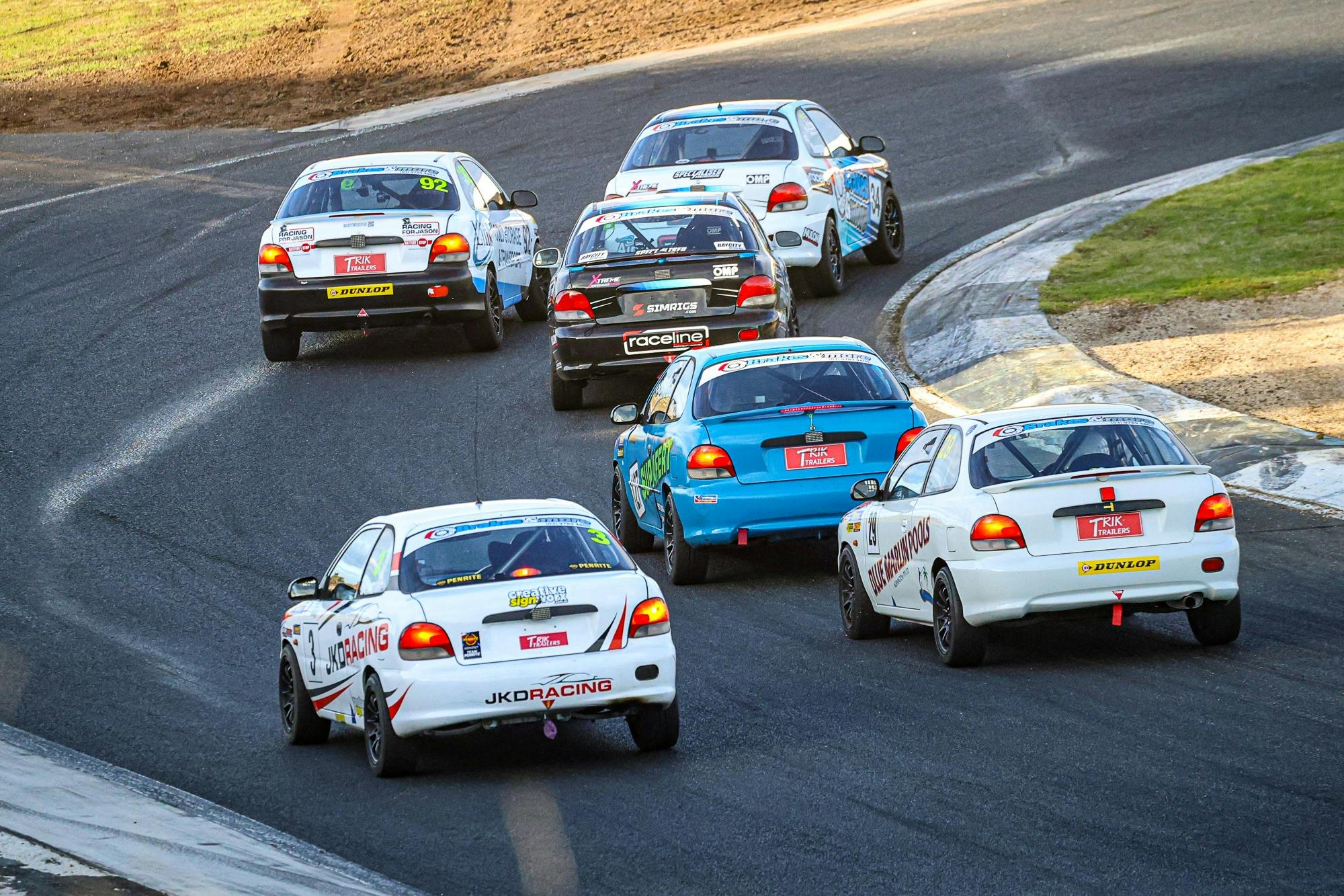 The back of six racing cars on a corner