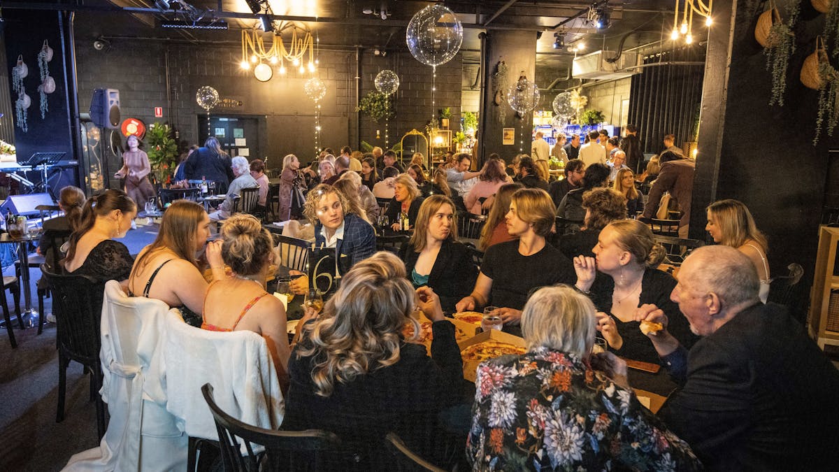 Vibrant room filled with people sitting at tables with clear balloons wrapped in fairy lights